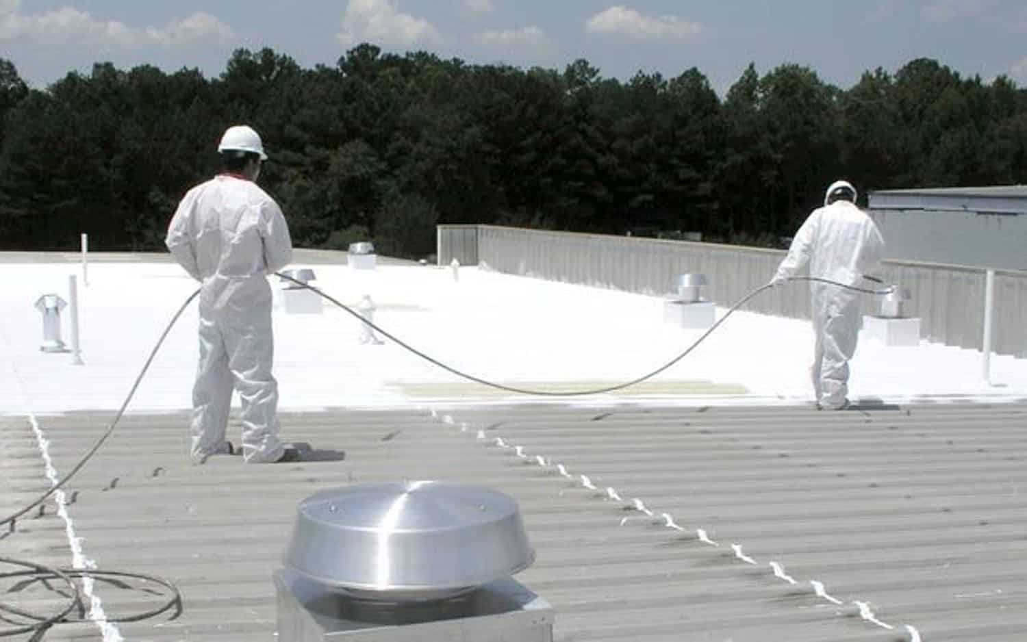 Two roofing Contractors spraying a Minneapolis commercial roof with a new protective roof coating