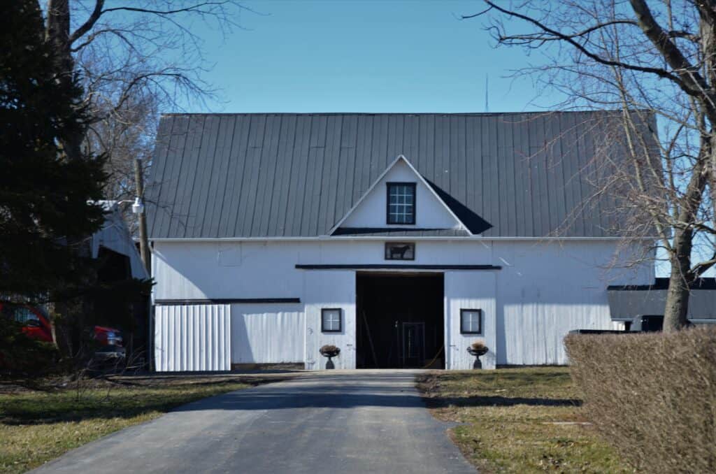 White barn with black metal roof installation by Minneapolis roofing company