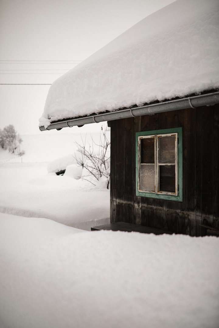 Corner of house covered in thick snow with a window and a half round gutter installation in Minneapolis